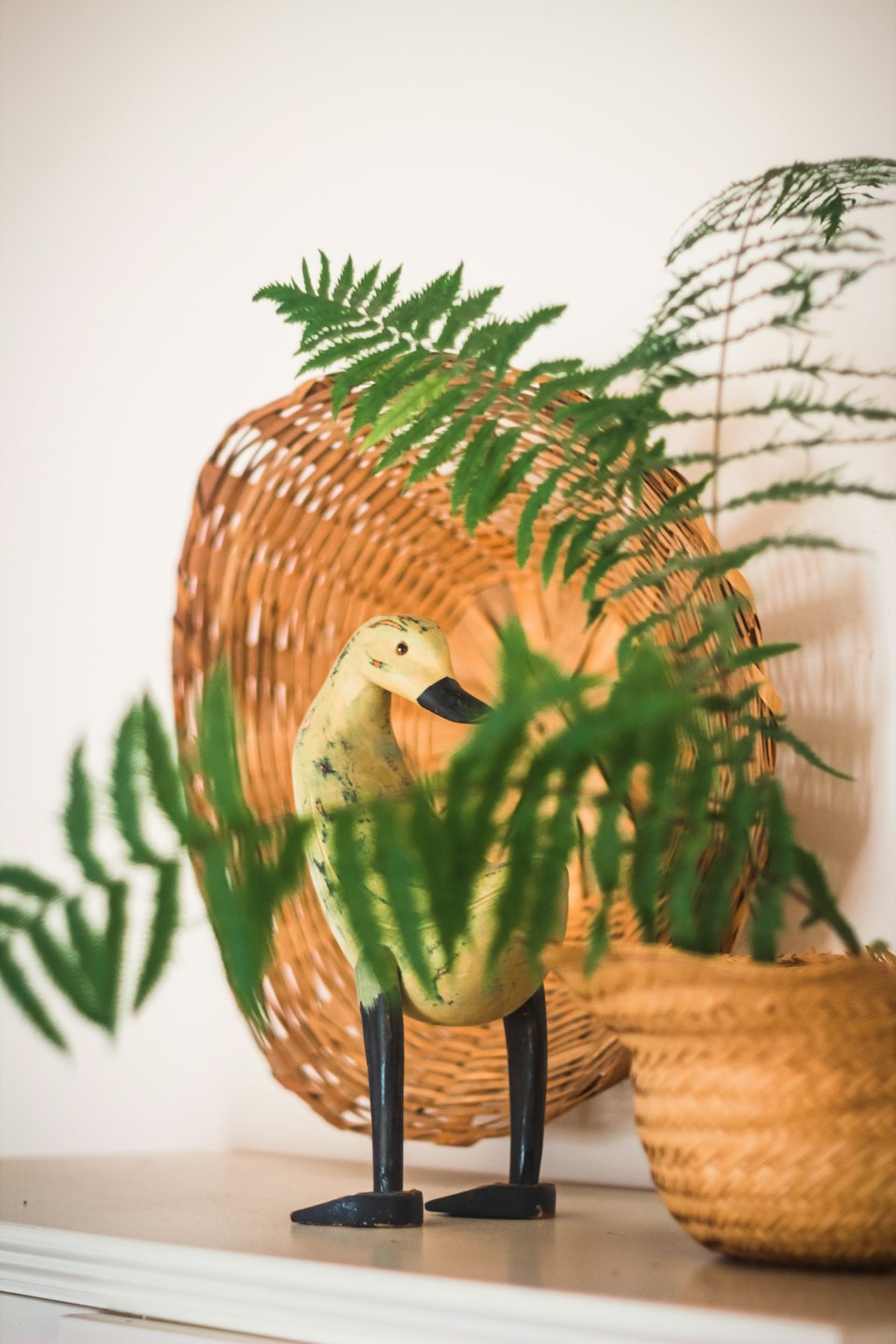 A yellow and black wooden duck figurine sits on a shelf.