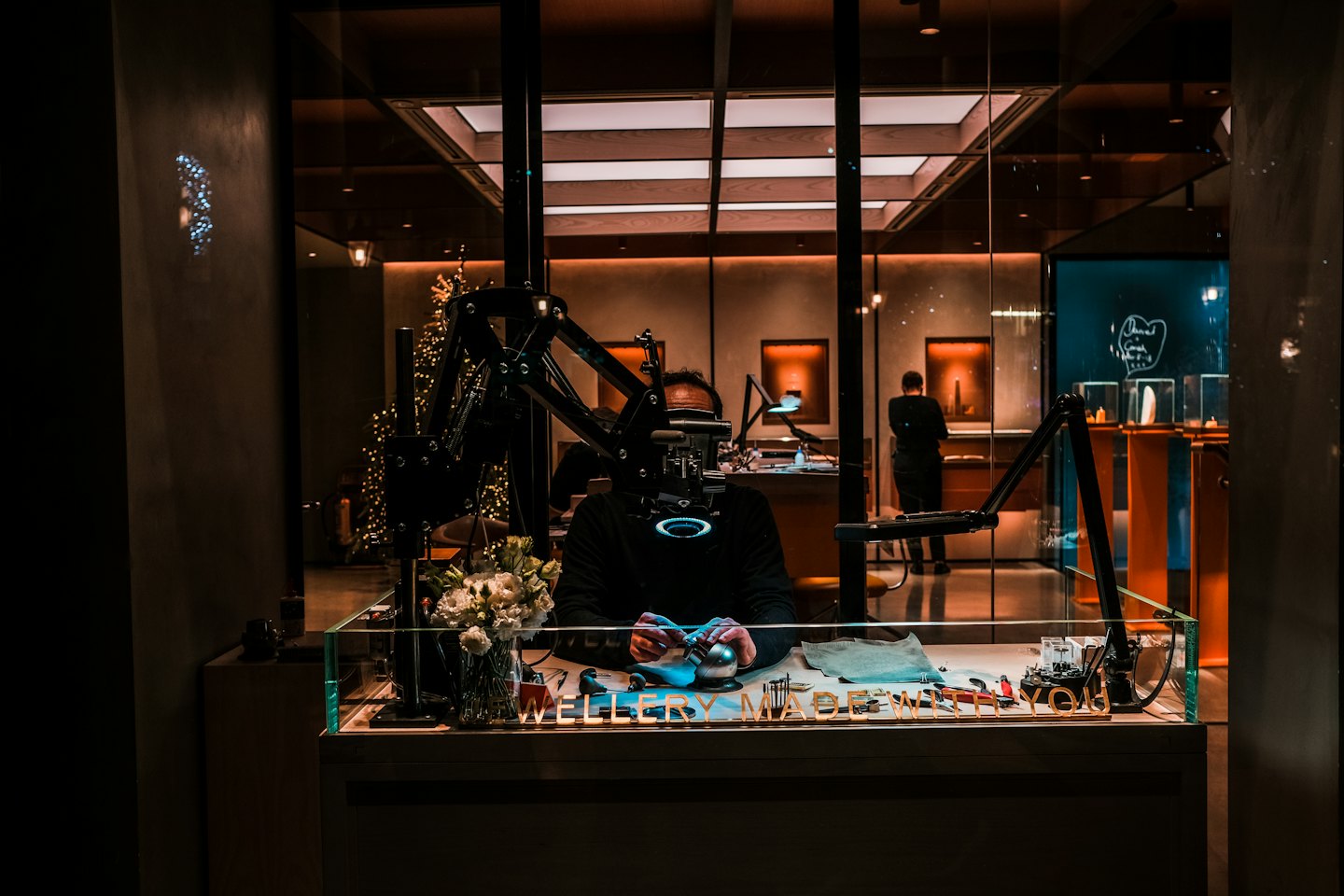 A jeweler works at a workbench inside a luxury shop.